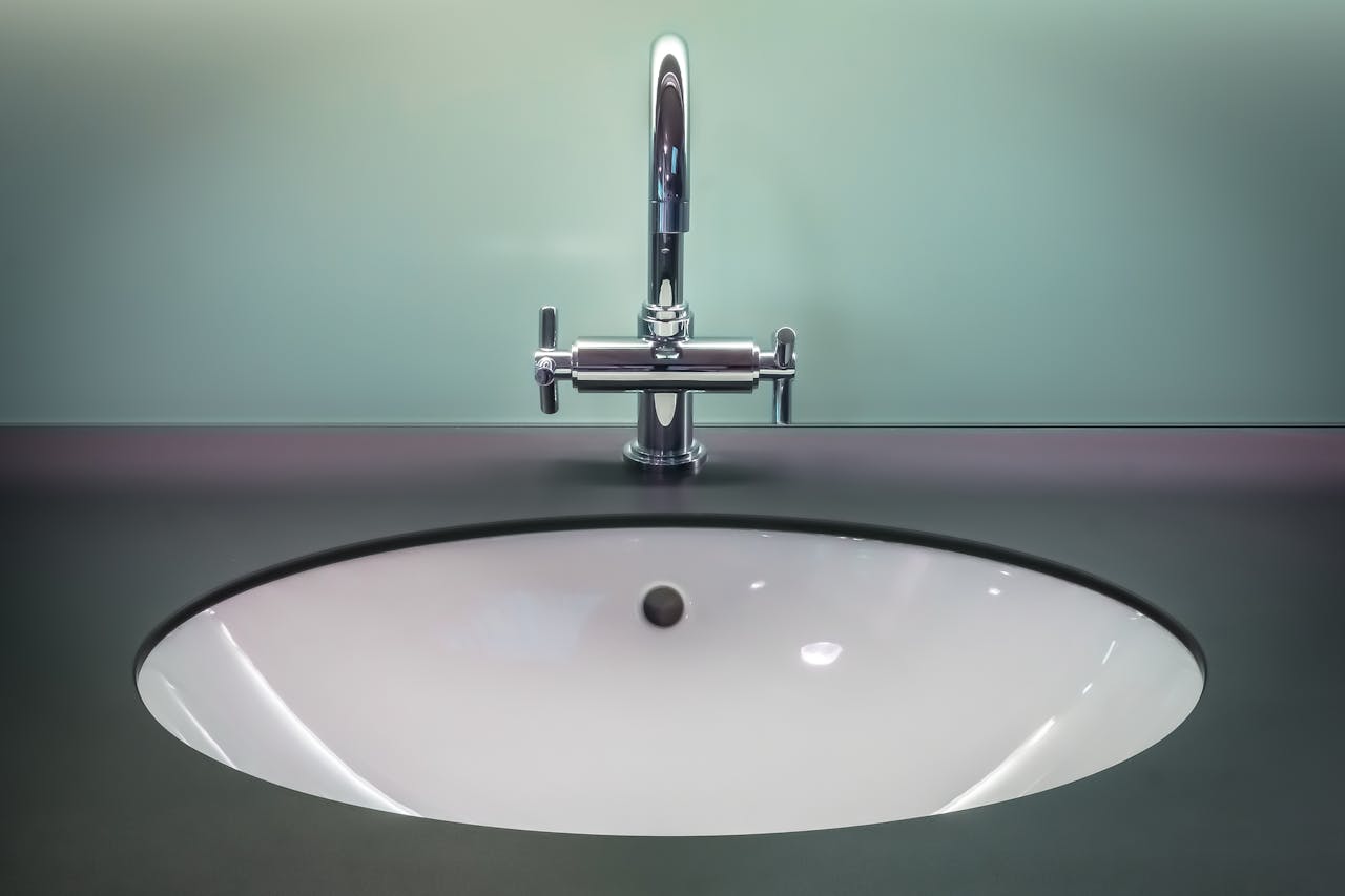 A sleek modern bathroom sink with a shiny stainless steel faucet on a dark vanity.